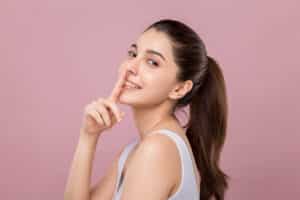 Woman smiling and pointing to her nose after rhinoplasty in Chicago, IL